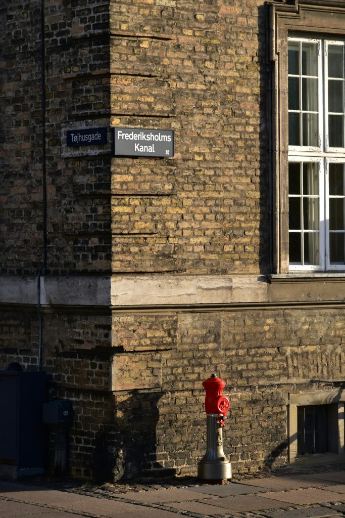 Gadehjørne med murstensfacade og gadeskilte i København.